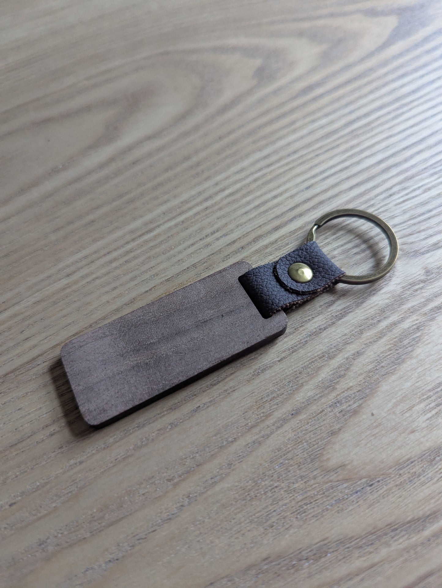 Brown leather keychain with a metal clasp on a wooden surface