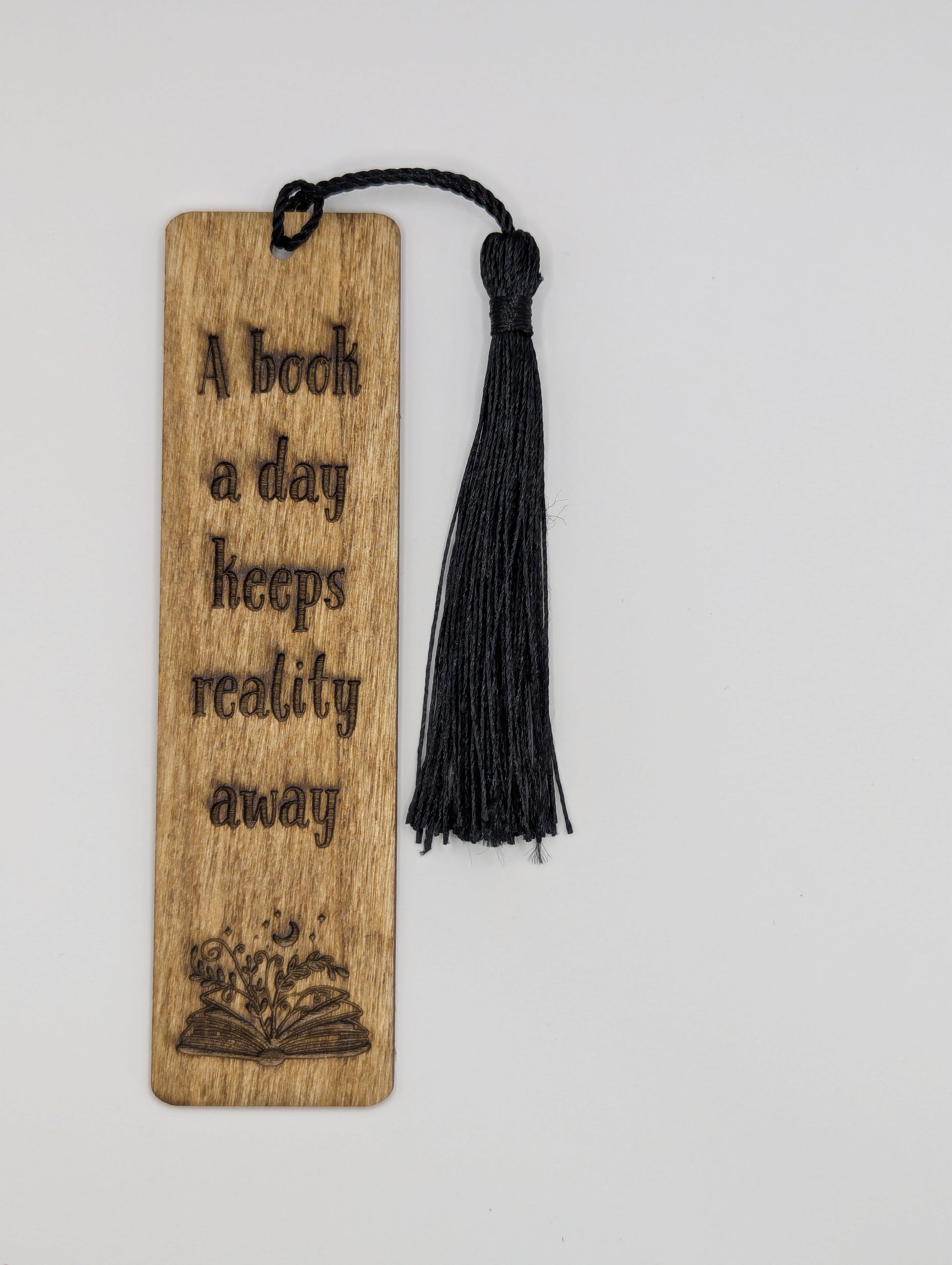 alt="Witty wooden bookmark engraved with ‘A book a day keeps reality away’"