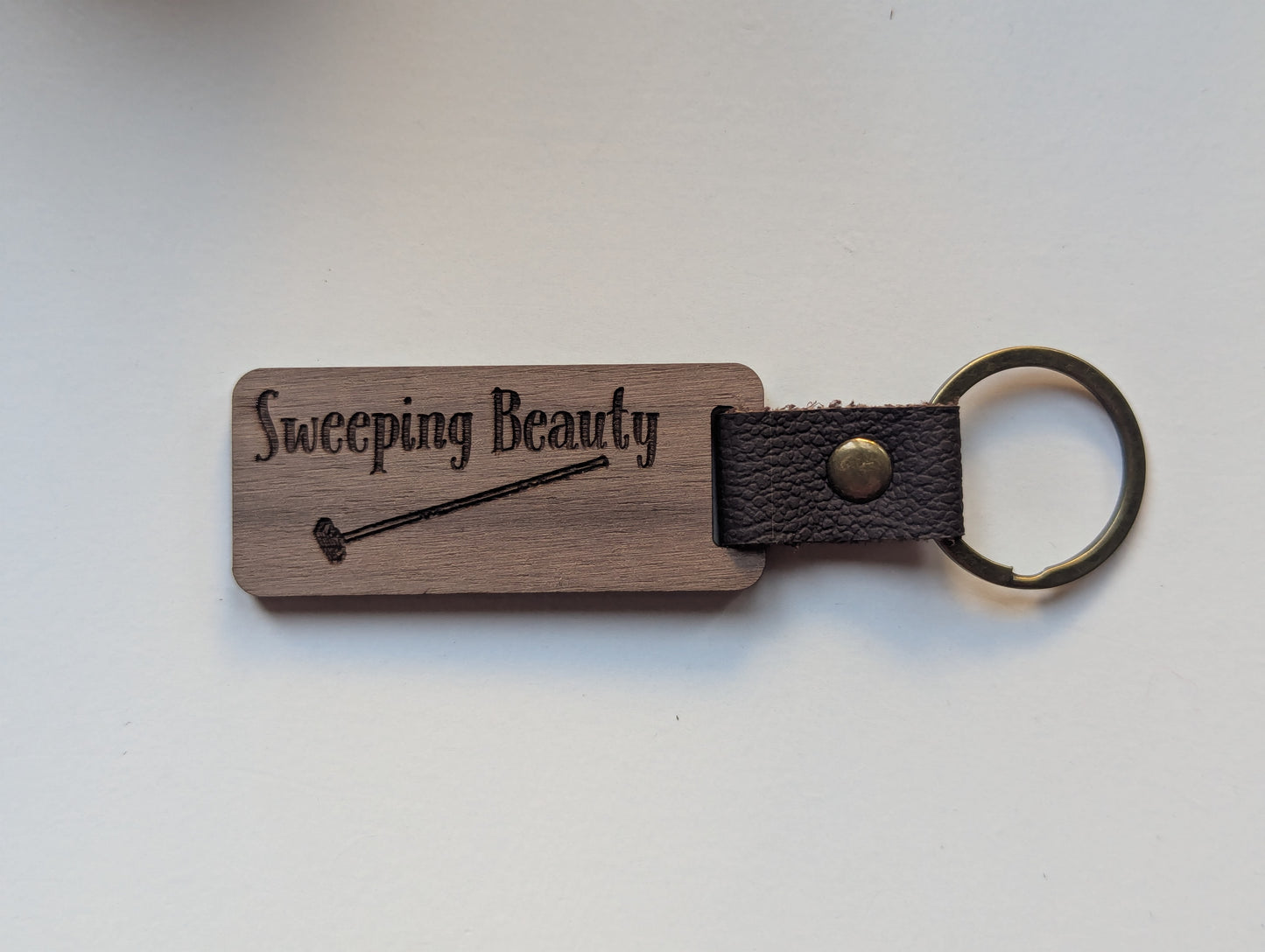 Wooden keychain with leather strap and engraved text on a white background