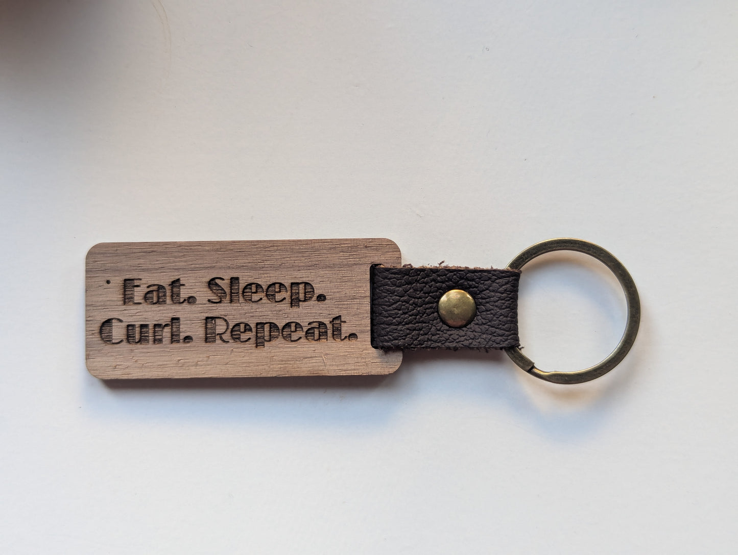 Wooden keychain with leather strap and engraved text on a white background