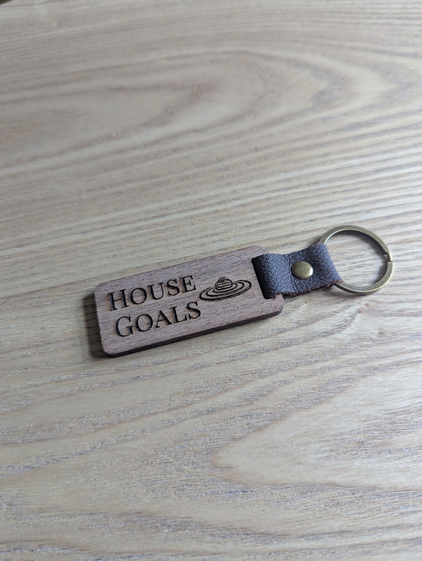 Wooden keychain with 'HOUSE GOALS' engraving on a wooden surface