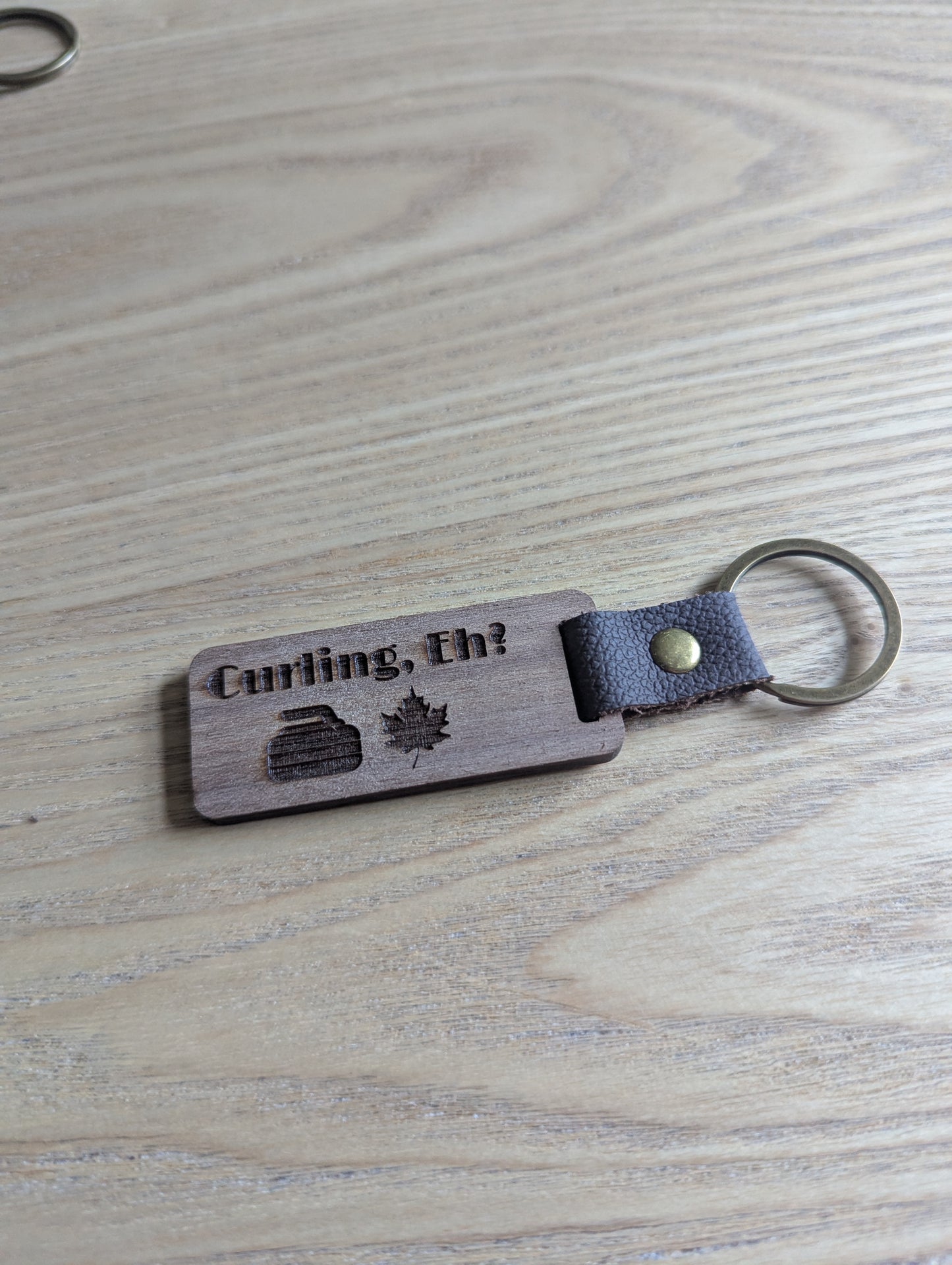 Wooden keychain with leather strap and engraved text on a wooden surface