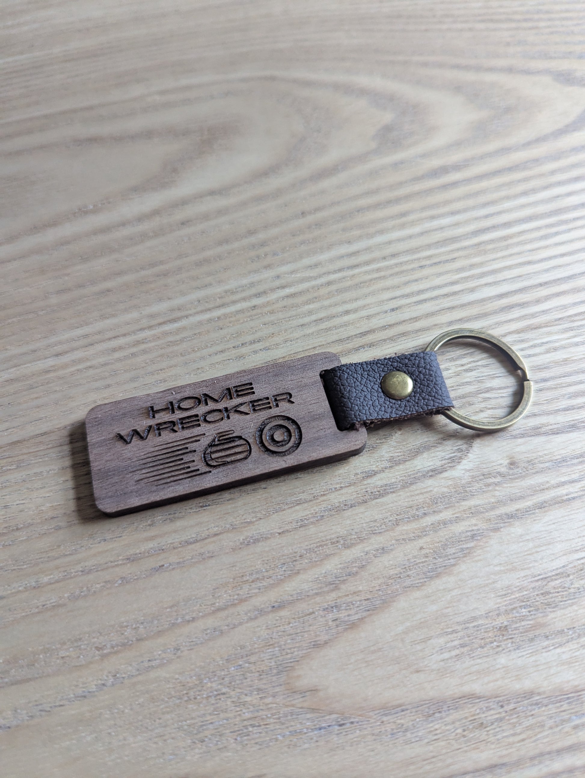 Keychain with 'Home Wrecker' engraving on a wooden surface