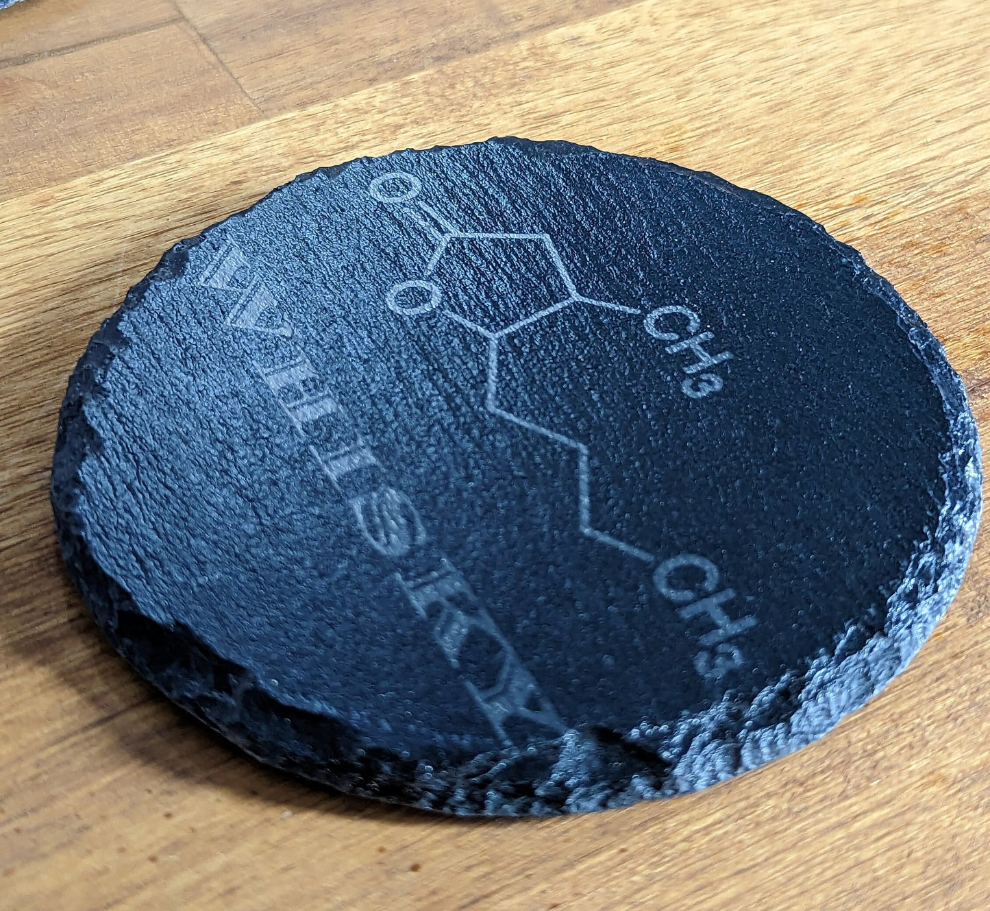 Set of 4 Charcoal Slate Coasters with Whisky Molecule Design next to a bottle of Bourbon.